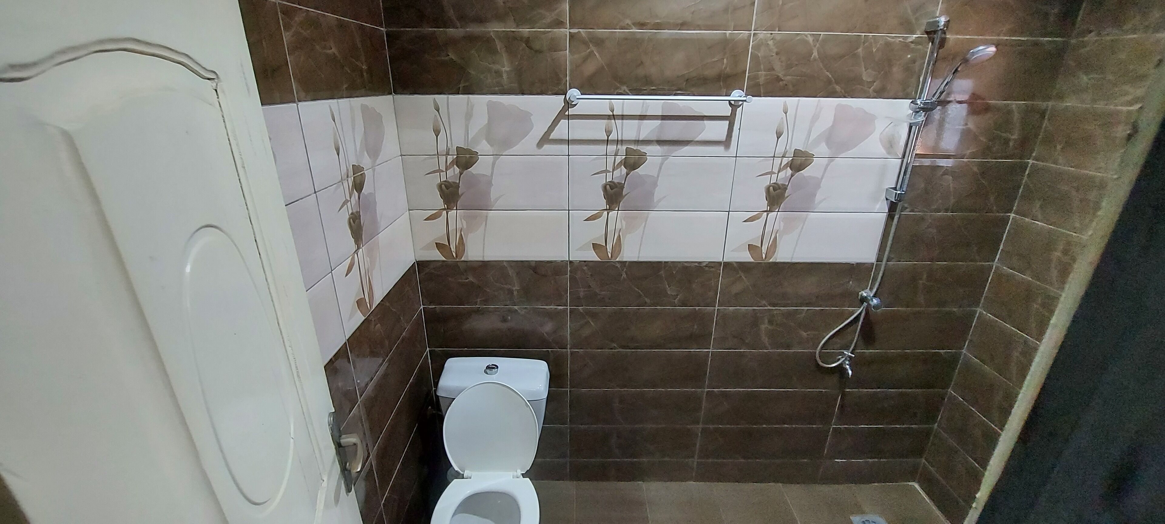 A bathroom with a toilet, a shower, and a towel rack.