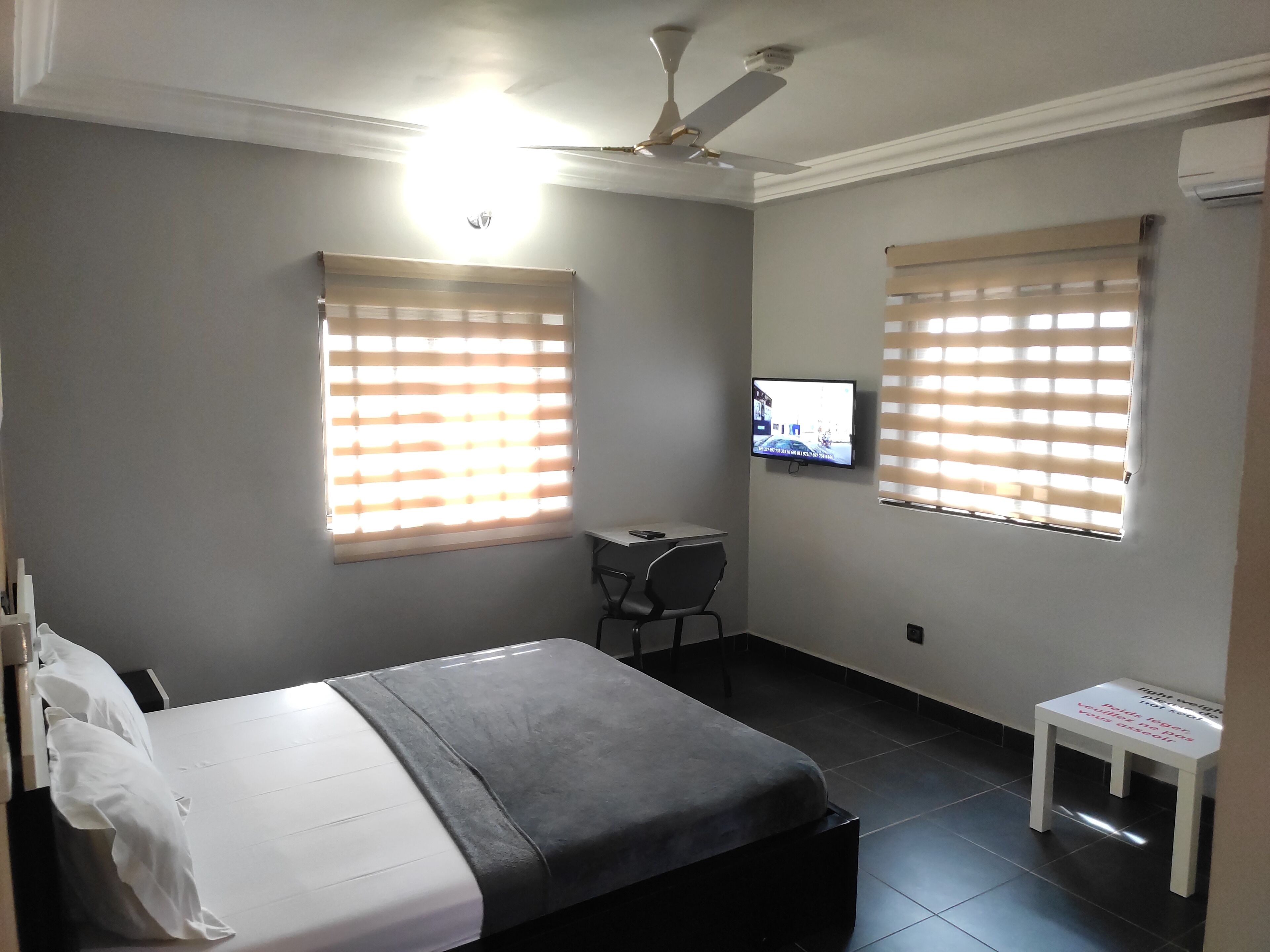 A hotel room with a bed, a desk, and a television mounted on the wall.