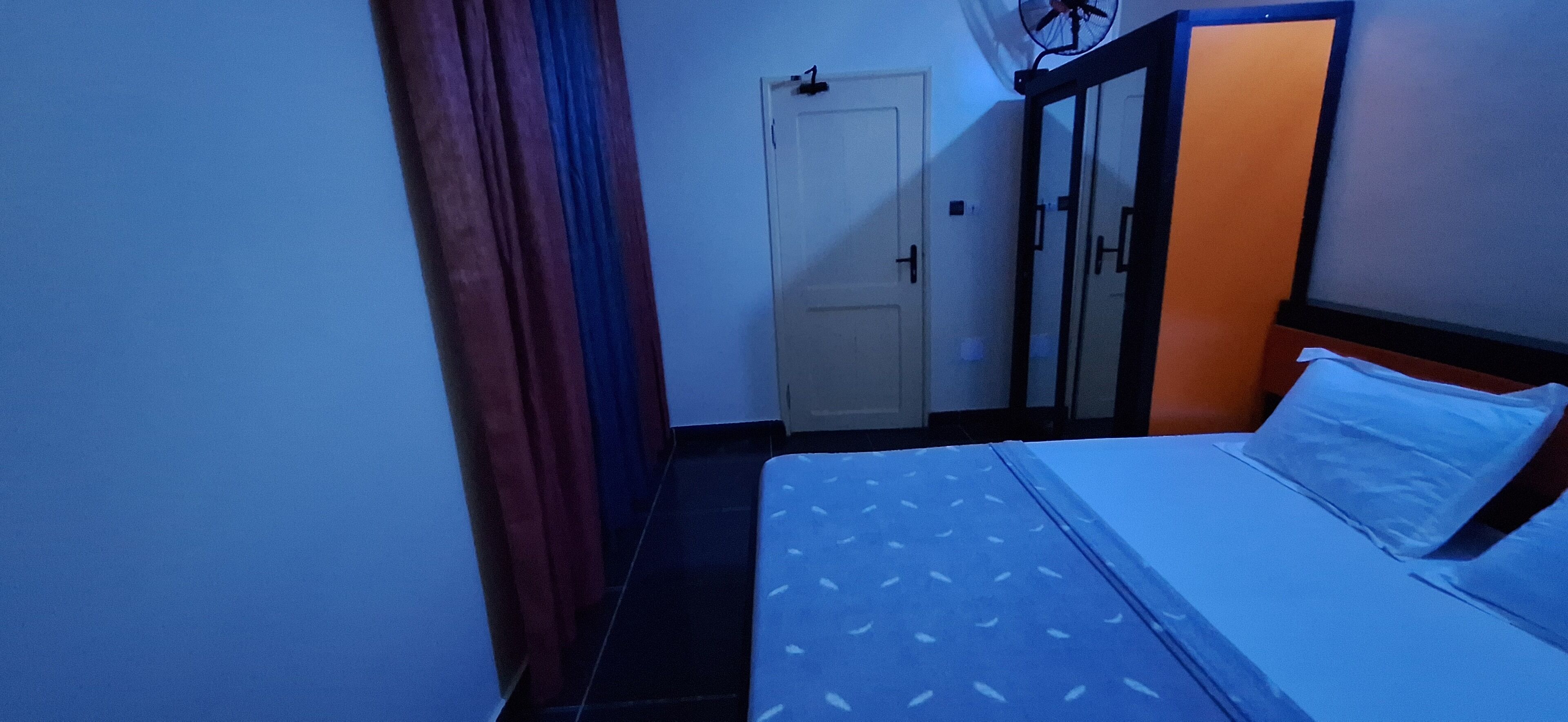 A narrow room with a bed, a wardrobe, and a door.