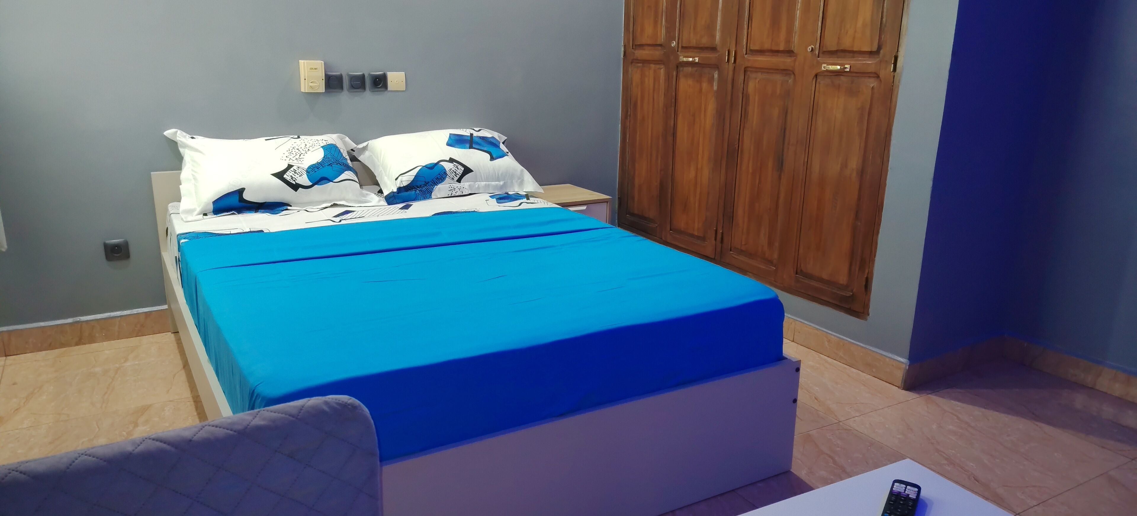 A bedroom with a bed, a wardrobe, a bedside table, and a chair.