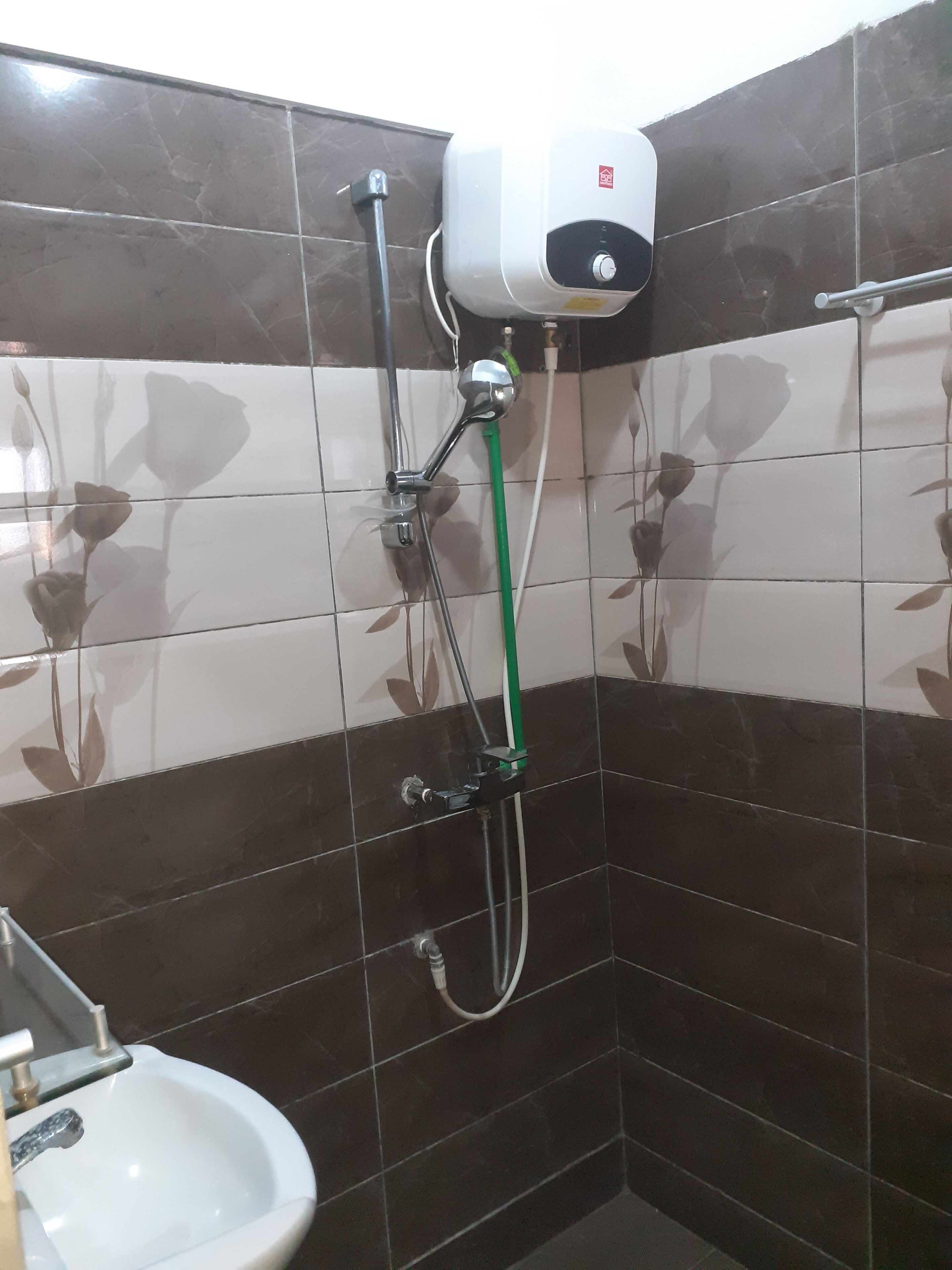 Un bagno con asciugamani ad aria, lavabo e doccia con tubo verde.