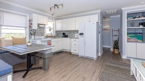 A modern kitchen with white cabinets, a black and white backsplash, and a built-in refrigerator. - Overlook the Intracoastal and walk to the beach! (North Topsail Beach)