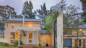 Une maison à deux étages avec un porche, une cheminée et un jardin.