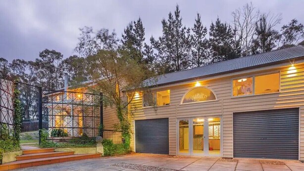 Une maison à deux étages avec un garage, une terrasse couverte et un jardin clos.