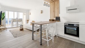 A modern kitchen with white cabinetry, a wooden dining table, and a large oven.