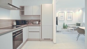 Eine moderne Küche mit integrierten Geräten, eine Essecke mit Sofa und Tisch sowie ein Wohnzimmer mit Couch und Kunstwerken.