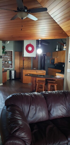 A modern kitchen with wooden cabinets, a central island, and bar stools.