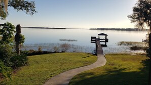 Escena tranquila junto al lago con un muelle de madera que conduce a un pabellón.