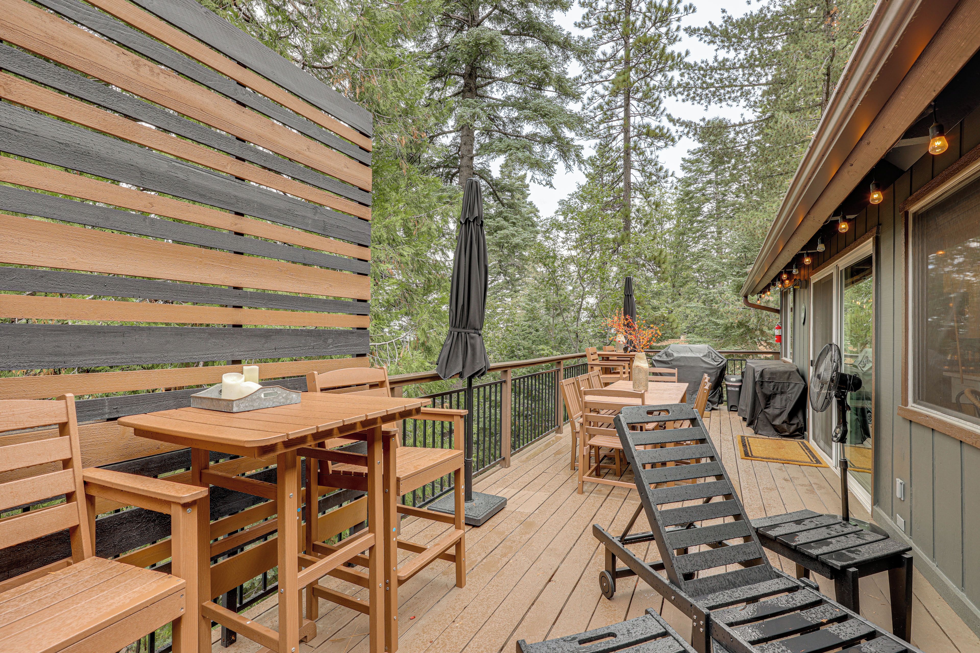 A wooden deck with outdoor furniture, including tables and chairs, and a barbecue grill.