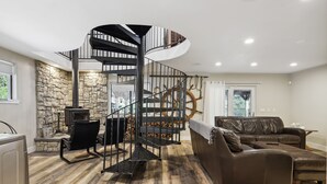 Amplia sala de estar con una escalera espiral, una pared de piedra, una chimenea y un sofá de cuero.