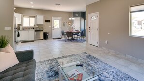 A spacious living area with a modern kitchen, a dining table with chairs, and a glass coffee table. - Tucson Vacation Rental w/ Community Pool! (Tucson)