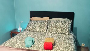 Ein Schlafzimmer mit Bett, Nachttisch, Lampe und einem Bild an der Wand.