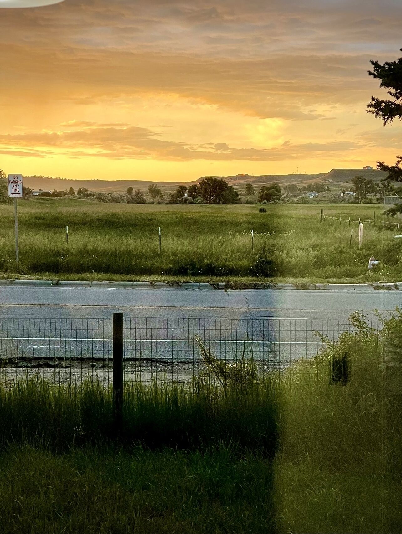 A rural landscape with a no parking sign, a fence, and a body of water.