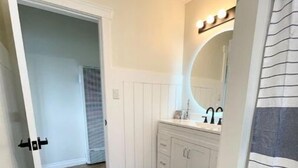 A bathroom with a white vanity, a large mirror, and a dark floor.