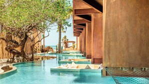 Un área de piscina con muelle de madera, una hamaca y vista al océano.