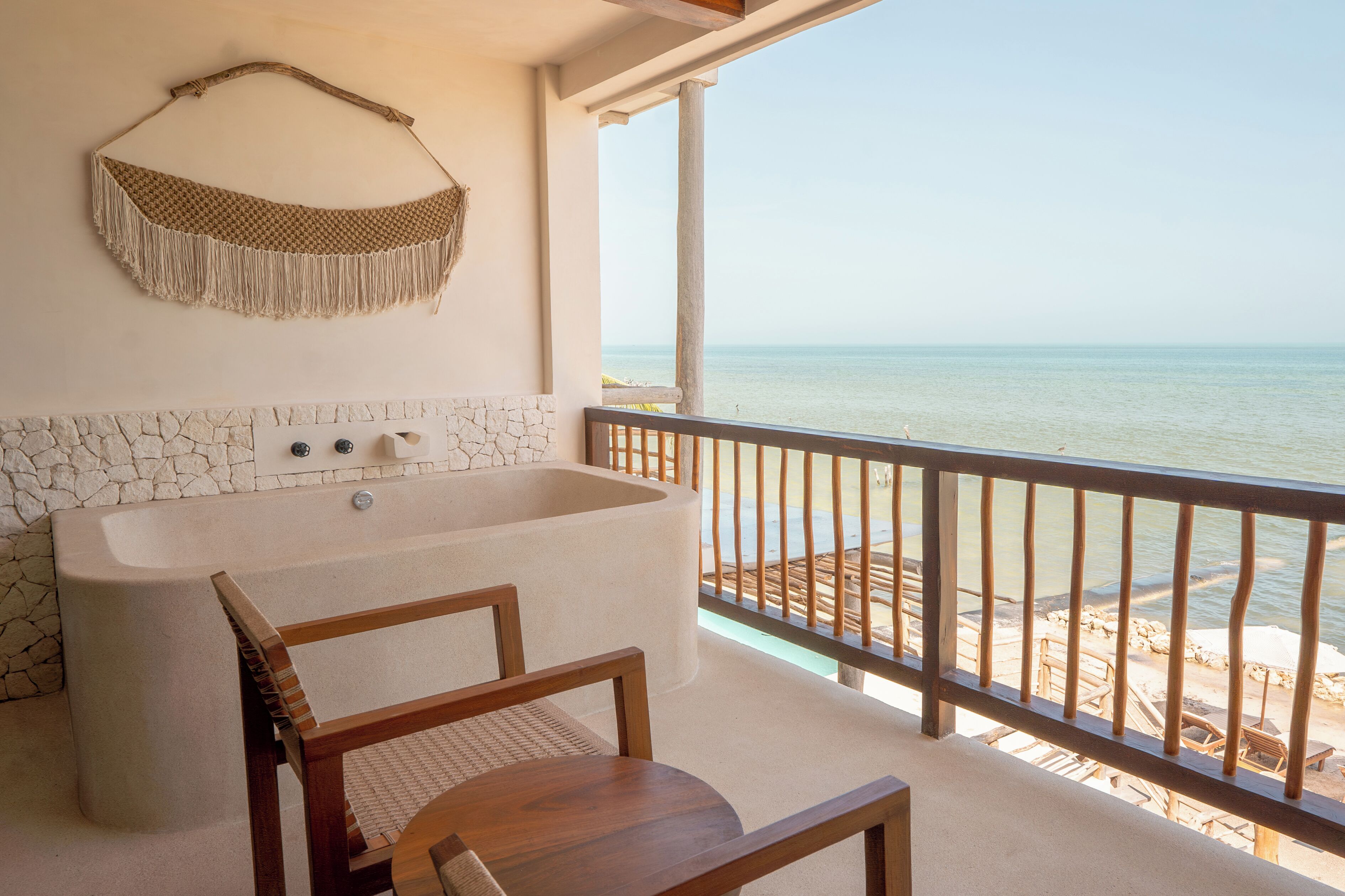 Ein Badezimmer mit einer großen Badewanne, einer Steinwand und Blick auf den Strand.