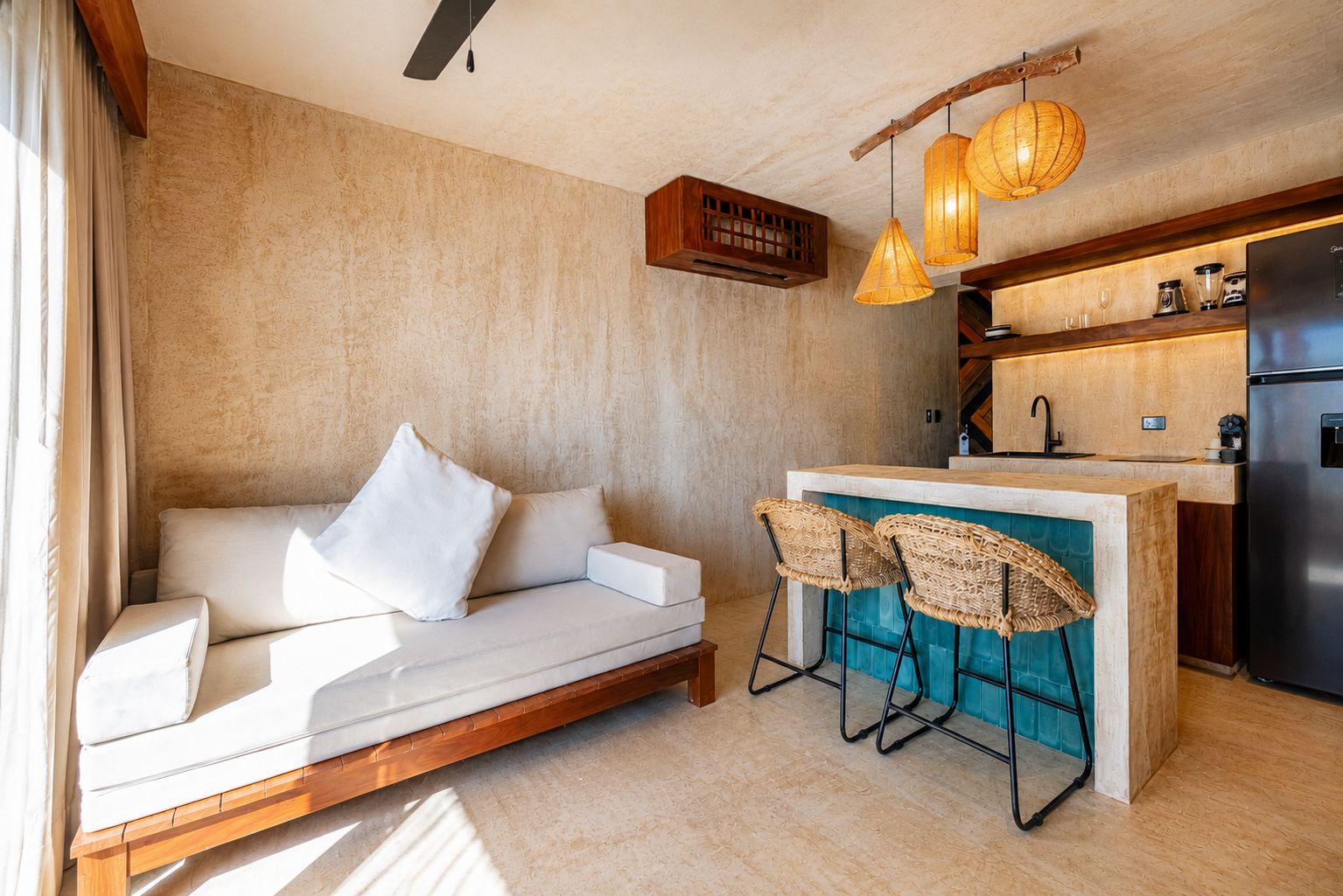 A modern kitchen with a built-in island, bar stools, and a refrigerator.