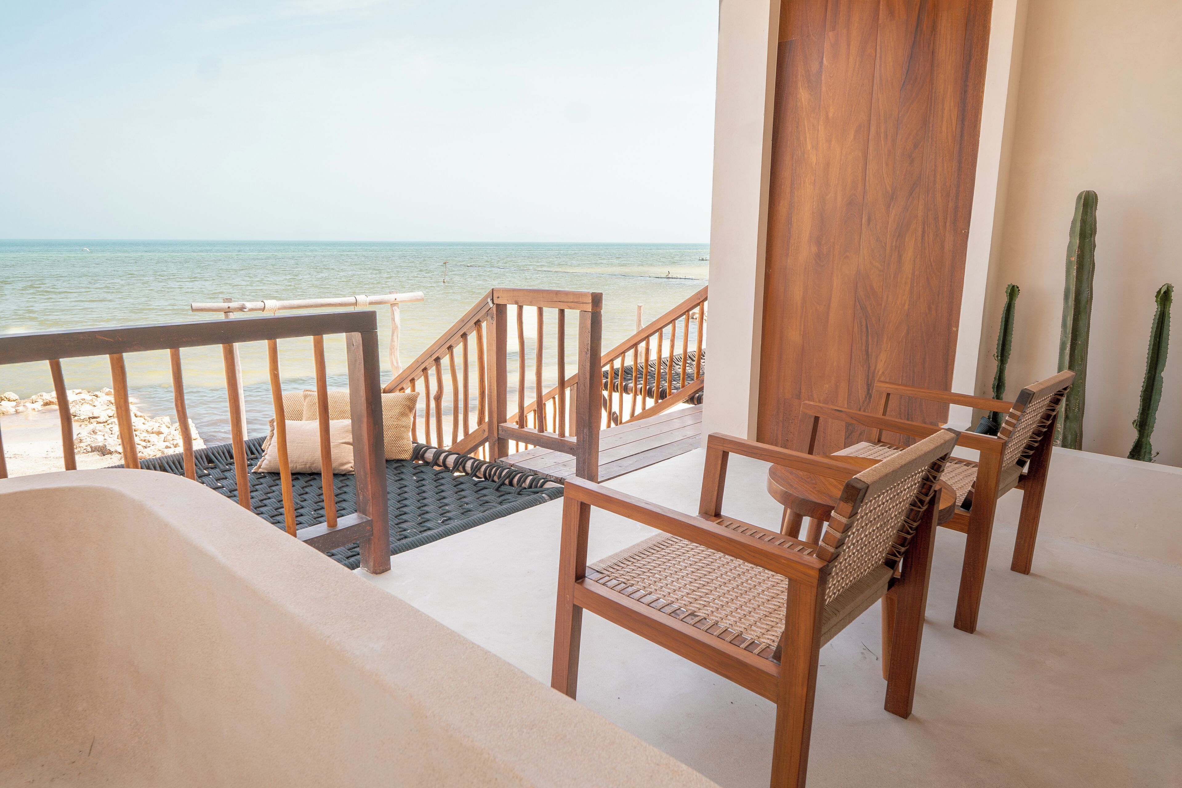 Una escalera de madera que lleva a un balcón con vistas a la playa.
