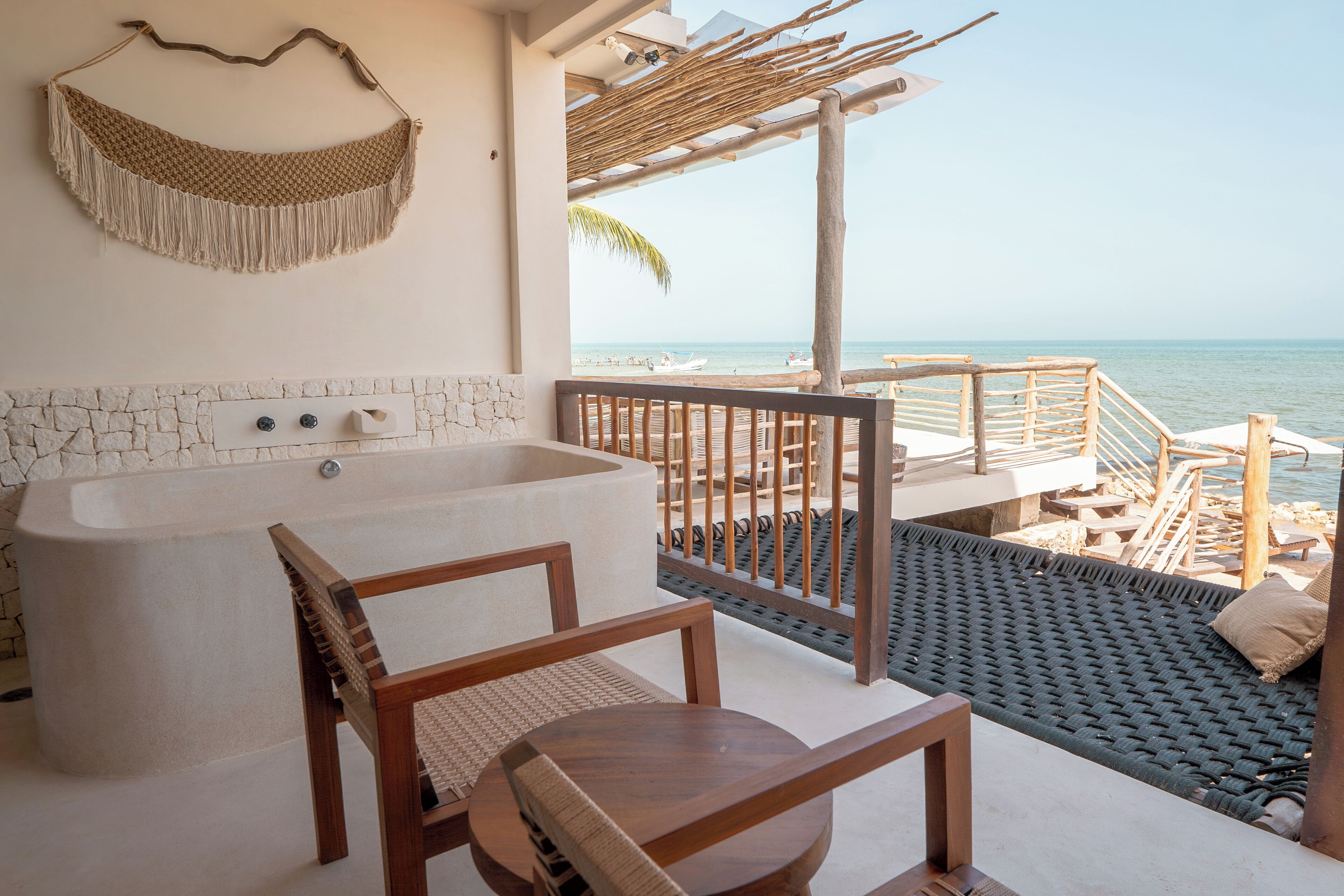 A bathroom with a large bathtub, wooden furniture, and a view of the beach.