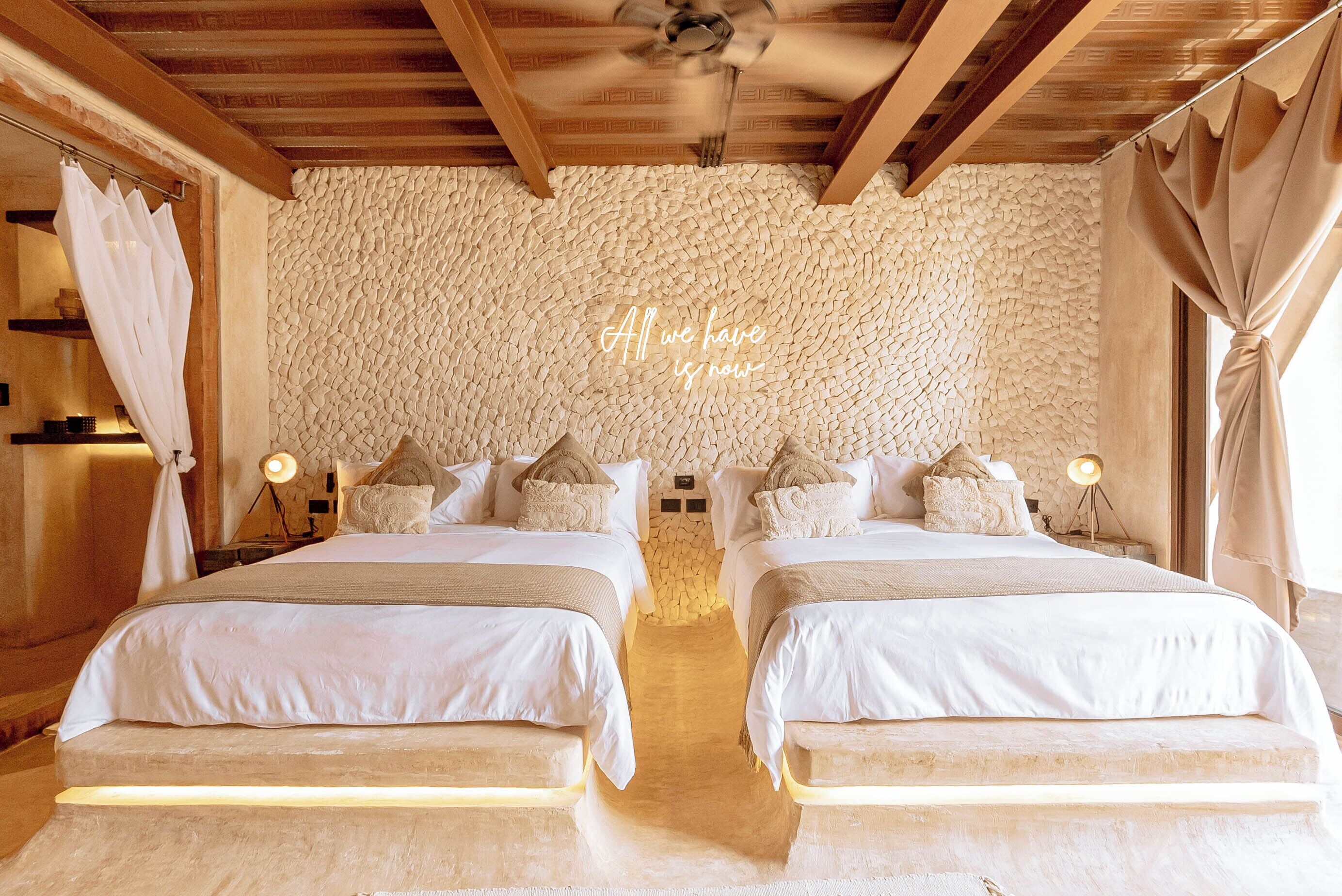 A double bed room with a stone wall and a ceiling fan.