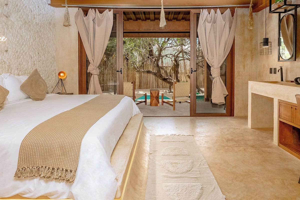 A bedroom with a bed, bedside lamp, and a view of an outdoor pool area.