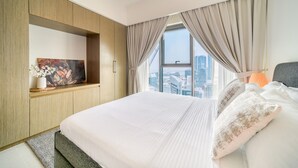 Een hotelkamer met een groot bed, een televisie bevestigd aan een houten kast, uitzicht op de stad door het raam en een stadszicht buiten.