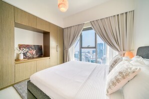 A modern hotel room with a large bed, a built-in TV, a city view, and a cozy ambiance. - City Lights and Luxury Living, Close to Dubai Mall (Dubai)