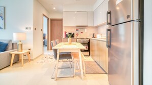 Een moderne keuken met roestvrijstalen apparatuur, een eethoek met een tafel en stoelen, en een woonkamer met een bank en een lamp.