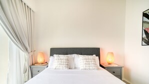 A neatly made bed with white linens and two bedside lamps on either side.