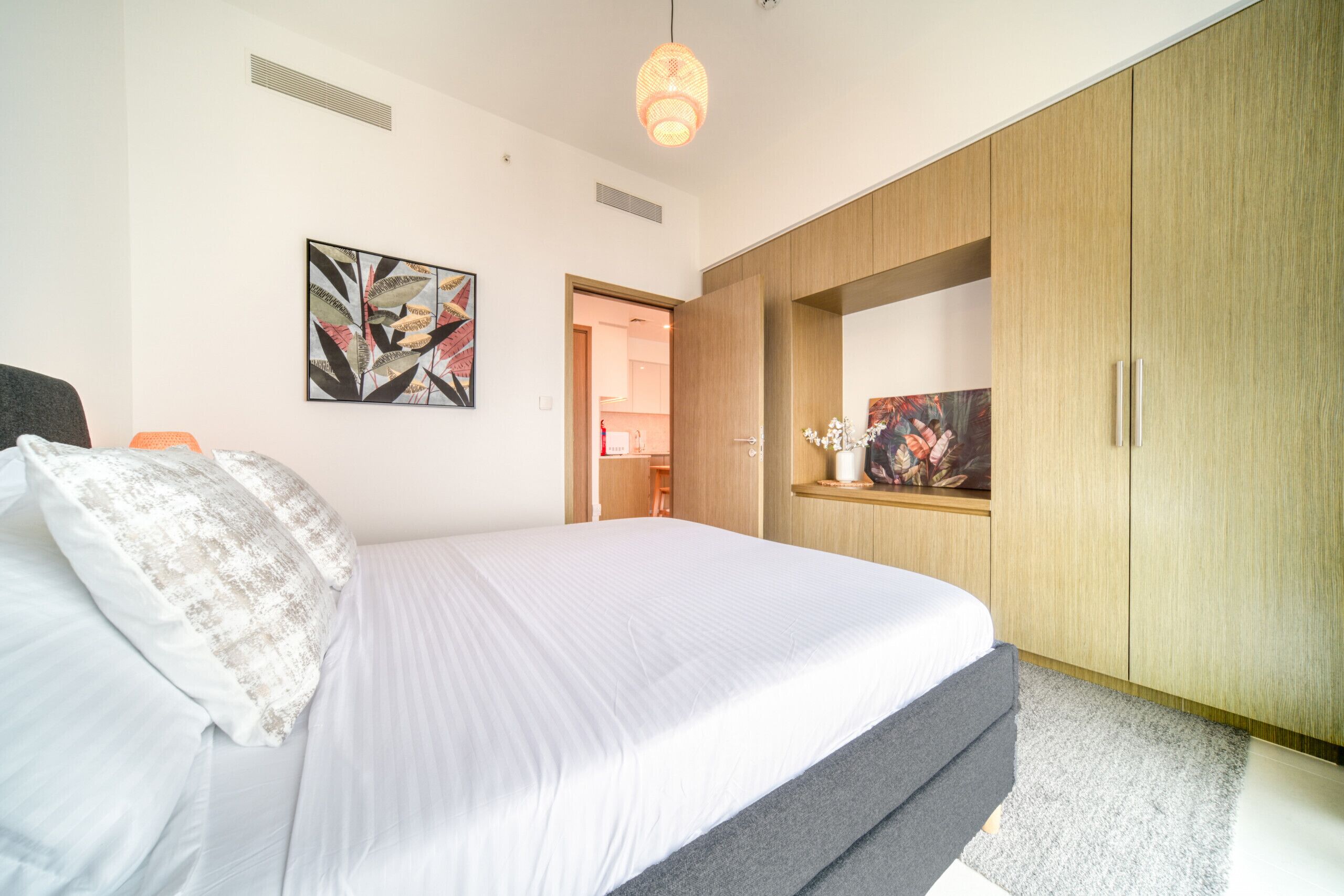 A bedroom with a bed, a wardrobe, and a door leading to a bathroom.
