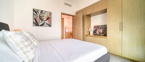 A bedroom with a bed, a wardrobe, and a door leading to a bathroom.