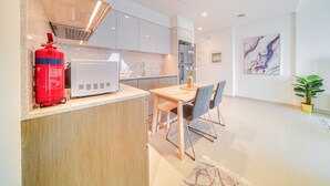 Een moderne keuken met witte kasten, een magnetron en een brandblusser.