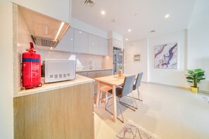 A modern kitchen with white cabinets, a microwave, and a red fire extinguisher. - City Lights and Luxury Living, Close to Dubai Mall (Dubai)
