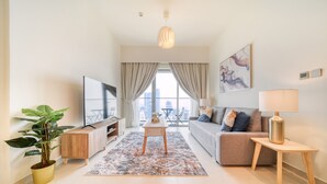 A modern living room with a sofa, TV, and a potted plant.