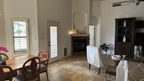 A spacious living room with a fireplace, a dining area with wooden furniture, and a kitchen area with granite countertops. - Entire Cozy Home in West El Paso (El Paso)