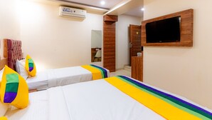 A hotel room with two beds, a TV mounted on the wall, and an air conditioning unit. - Itsy Hotels Elegant (Mumbai)