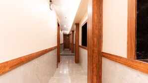 A corridor with wooden trim and marble flooring, leading to a door at the end. - Itsy Hotels Elegant (Mumbai)