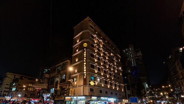 A multi-story hotel with illuminated signage, a prominent 'HOTEL ELEGANT' sign, and a 'HOTEL PENINSULA SUITE' sign. - Itsy Hotels Elegant (Mumbai)