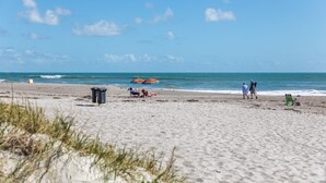 A beach with a clear sky, a few people, and beach chairs.