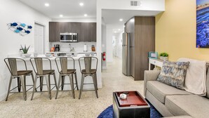 A modern kitchen with a central island, bar stools, and a dining area.