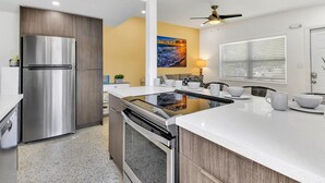 A modern kitchen with a stainless steel refrigerator, a built-in oven, and a large island with a black countertop.