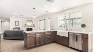 A modern kitchen with dark wooden cabinets, a white countertop, stainless steel appliances, and pendant lighting.
