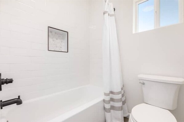 A bathroom with a bathtub, toilet, and a window. - Gorgeous 5 Bedroom / 4 Bath Home with Heated Pool! (Tucson)