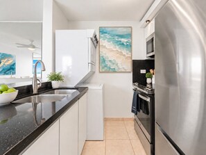 A modern kitchen with a stainless steel refrigerator, a black countertop, and a white dishwasher. - Beachfront 2b/2b  Isla Verde  Marbella Oeste (Carolina)