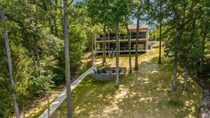 A two-story building with a stone pathway leading to a seating area with chairs. - Lake Loop Retreat w/Movie Theater & Private Dock (Speedwell)