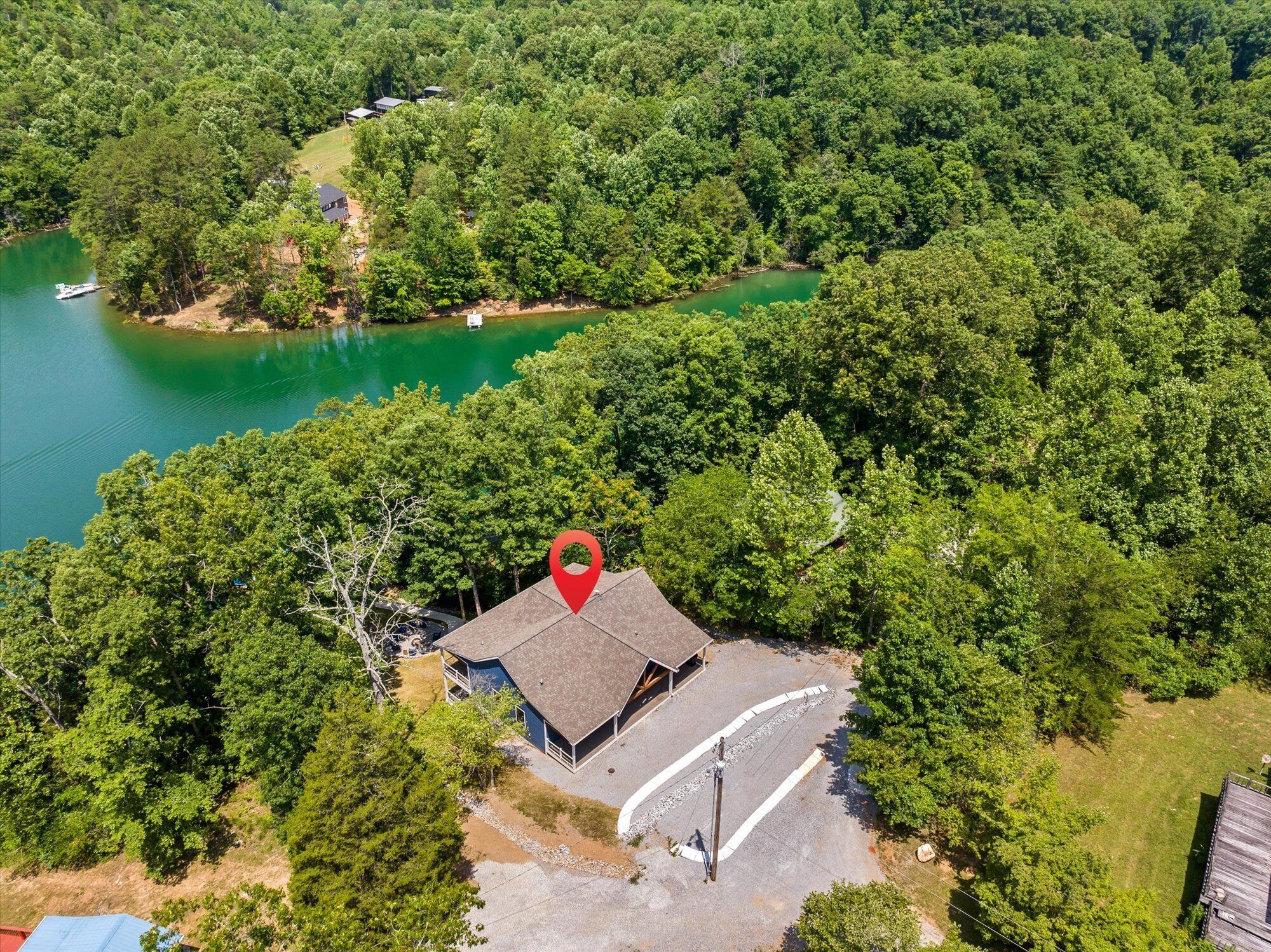 Eine Vogelperspektive zeigt ein Haus, umgeben von dichtem Wald und einem See.