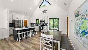 A modern kitchen with white cabinets, stainless steel appliances, and a black island. - Lake Loop Retreat w/Movie Theater & Private Dock (Speedwell)