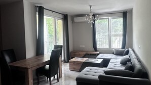 A modern living room with a dining area, a sofa set, and a chandelier.