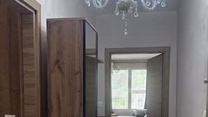A hallway with wooden doors, a chandelier, and a view into a room with a window and a sink.
