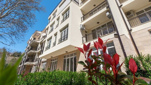 A multi-story building with balconies, large windows, and air conditioning units.